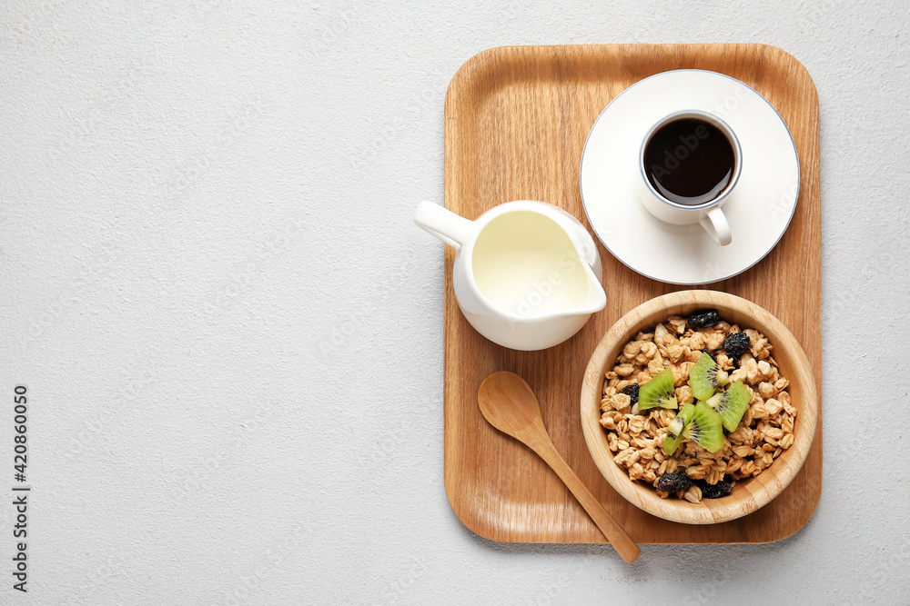 Wooden tray with tasty breakfast on light background