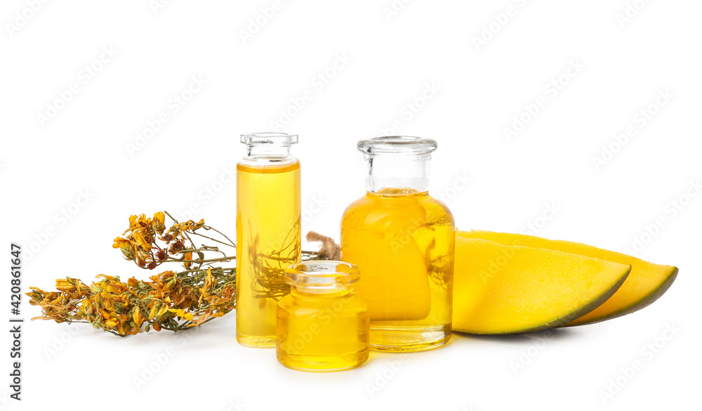 Bottles of essential oil, herbs and mango pieces on white background
