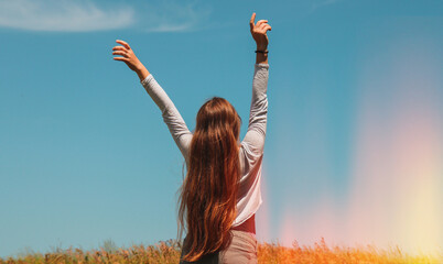 a long-haired blonde in the middle of a field with wheat raised her hands up and enjoys the air and 