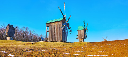 Canvas Print - Panorama with plowed field and medieval wooden windmills, Pyrohiv Skansen, Kyiv, Ukraine