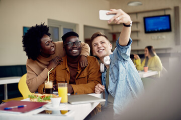Wall Mural - Group of happy students taking selfie with smart phone in cafeteria.