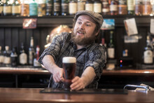 Barman Serving Beer From Bar In Traditional Irish Public House