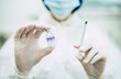 © My Ocean studio - Doctor, nurse, or a scientist in blue gloves holding covid-19 vaccine disease preparing for human clinical trials vaccination shot, medicine, and drug concept.