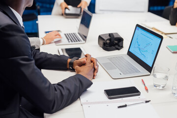 Businessman with laptop at conference table meeting, cropped