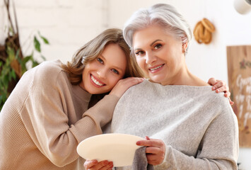 Wall Mural - Happy senior woman with daughter hugging at home