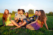 © Connect Images - Group of young adults sitting in field listening to acoustic guitar