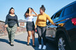 © Connect Images - Young woman and two teenage sisters opening car door, UK