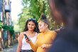 © Connect Images - Young woman with teenage sisters looking at smartphone by park, over shoulder view