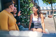© Connect Images - Young woman and her teenage sisters sitting on outdoor table chatting
