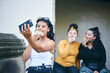 © Connect Images - Young woman taking selfie with teenage sisters while eating cakes in doorway