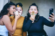 © Connect Images - Young woman and teenage sisters posing for selfie while eating cakes