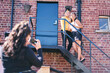 © Connect Images - Young woman and her teenage sister being photographed  on fire escape
