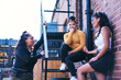 © Connect Images - Young woman and her teenage sisters chatting on fire escape