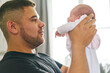 © Connect Images - Father bonding with baby in arms at home