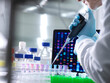 © Connect Images - Scientist pipetting DNA samples into microcentrifuge tubes during an experiment in the laboratory with the DNA profile on the monitor screen.