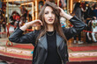 © Connect Images - Woman touching hair and posing in front of carousel