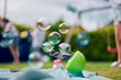 © Connect Images - Soap bubble machine, family playing in garden in background