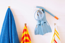 Towels, Snorkel Tube And Flippers Hanging On Bathroom Wall