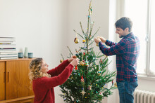 Couple Decorating Christmas Tree At Home