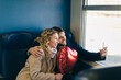 © Connect Images - Couple taking selfie with heart shaped balloon inside train