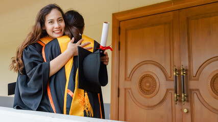 Wall Mural - The Asian university graduates in graduation gown and a mortarboard cap with a degree certificate in hand celebrating education achievement in the commencement ceremony. Congratulations to graduations