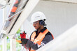 © Connect Images - Male engineer wearing hardhat and ear protectors working on construction site.