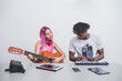 © Connect Images - Young woman with long pink hair and young man with short dreadlocks playing guitar and keyboard.