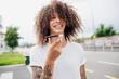 © Connect Images - Portrait of man with tattooed arms and long brown curly hair, using mobile phone.