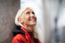 Portrait Of Smiling Woman With Long White Hair, Standing Outdoors, Looking Up.
