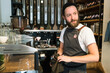 © Connect Images - Bearded barista wearing apron working behind counter in a cafe.