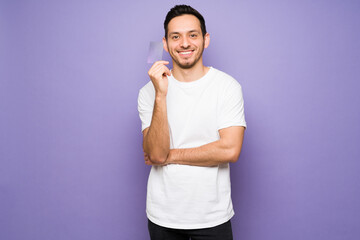 Canvas Print - Happy man showing a credit card in a bright background