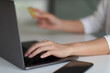 © Natee Meepian - Close up hand of woman using laptop computer and credit card for shopping online at home.