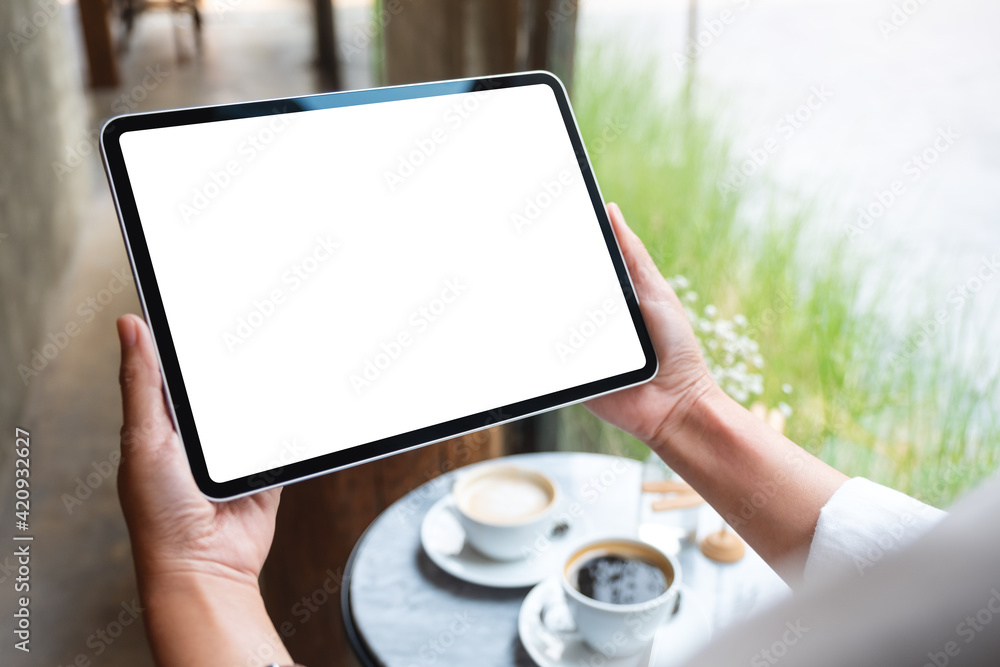 Mockup image of a woman holding digital tablet with blank white desktop screen in cafe - obrazy, fototapety, plakaty 
