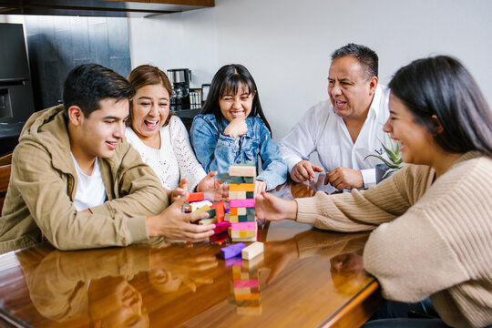 Latin family, mother, father, son and daughter excites with wooden block game  at home in Mexico