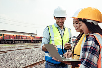 Engineers working on railway train statation and holding laptop for plan and meeting. Portrait of professional leadership of engineering teamwork. Warehouse and successful concept. 