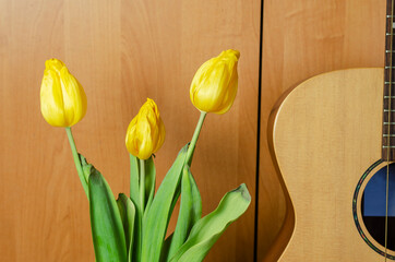 bouquet of fading flowers and an acoustic guitar on brown backgr