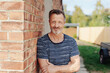 © contrastwerkstatt - Smiling mature man leaning on wall of house