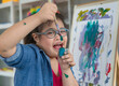 © Bangkok Click Studio - Happy girl with Down syndrome painting on easel