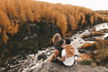 Happy in love romantic young cheerful couple man and woman married travel hiking walk together among the autumn forest and mountains looking for adventure enjoy the local nature, selective focus