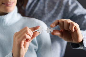 Man and woman are trying to connect white puzzles together