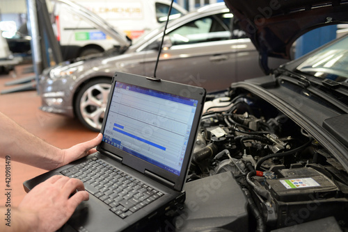 mechanic in a workshop checks and checks the electronics of the car - software update with a modern computer