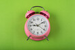 Leinwandbild Motiv A pink color table clock with a Green background flat lay shot