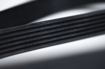 Close-up of a poly V-belt of a generator on a gray background in shallow depth of field. Background for rubber products of auto parts