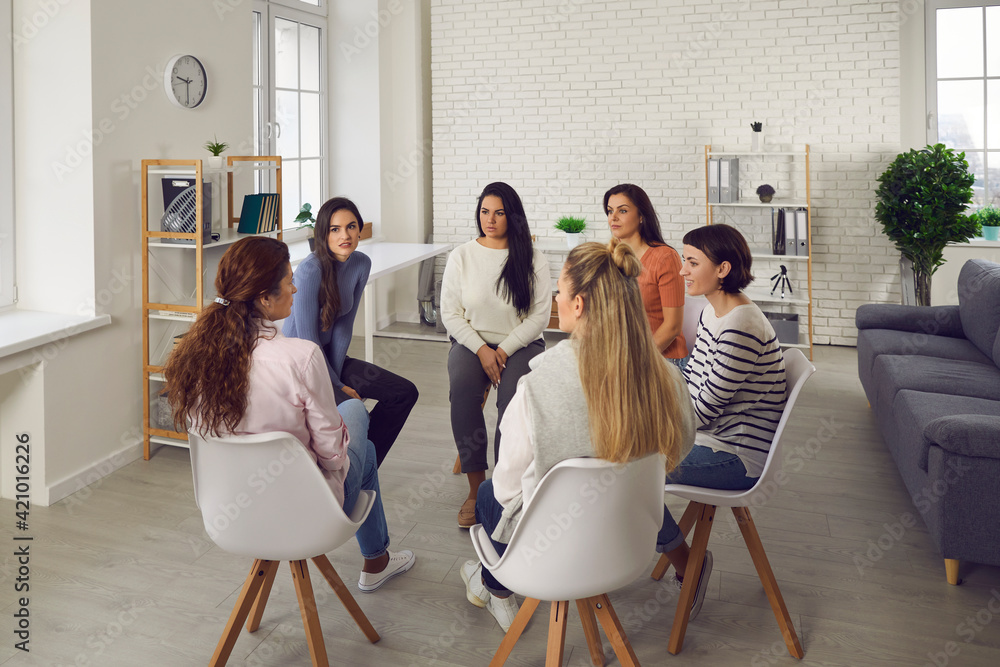 Young women telling their stories in therapy session or support group meeting. Female team talking, sharing news, discussing life situations, giving each other advice, working out solutions together - obrazy, fototapety, plakaty 