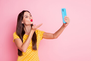 Poster - Photo of flirty young woman send air kiss hand phone take selfie wear yellow dotted t-shirt isolated on pink color background