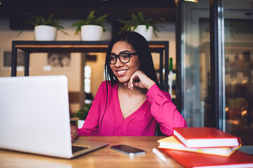 Wall Mural - Smiling ethnic female student using laptop in cafe