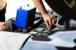 © NVB Stocker - Auto mechanic worker checking and changing car battery. Car maintenance and auto service garage concept.