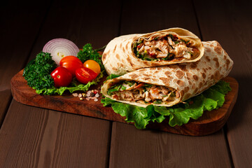 Shawarma, roll in lavash , grilled meat, with vegetables, sandwich , on a wooden brown background, horizontal, copy spase
