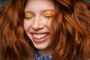 Wall Mural - Young ginger joyful woman laughing with eyes closed indoors