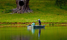 Two People On A Fishing Boat Fishing On A Calm Lake In Blenheim Palace ,Oxford